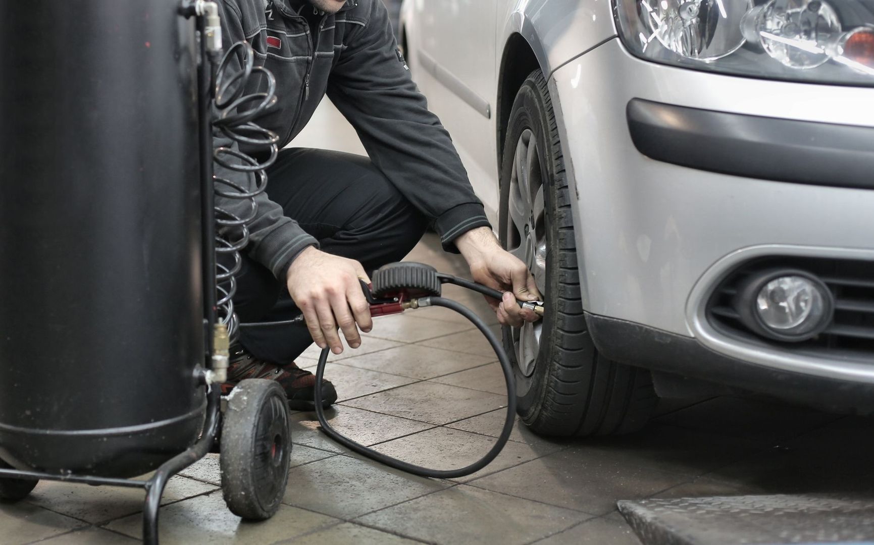 Mechanic checking a car tire with a handheld air-pressure gauge