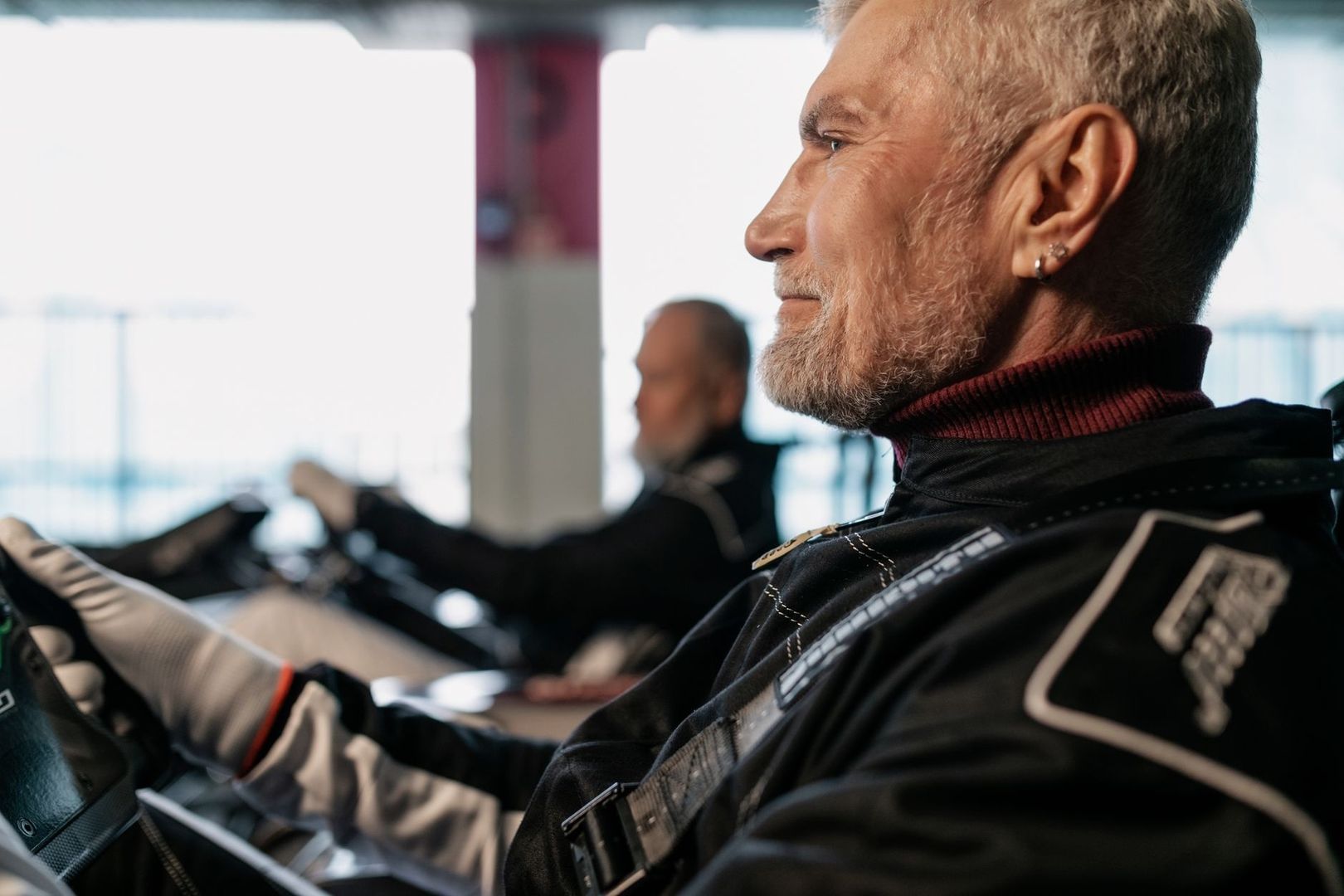 Race driver seated in a cockpit wearing a black head restraint system